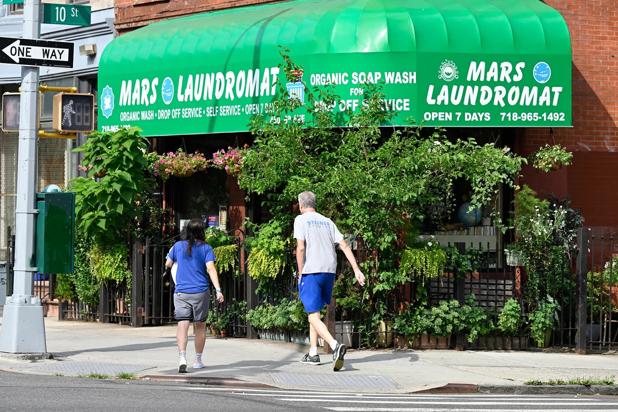 The green awning and garden outside Mars Laundromat, seen from the sidewalk